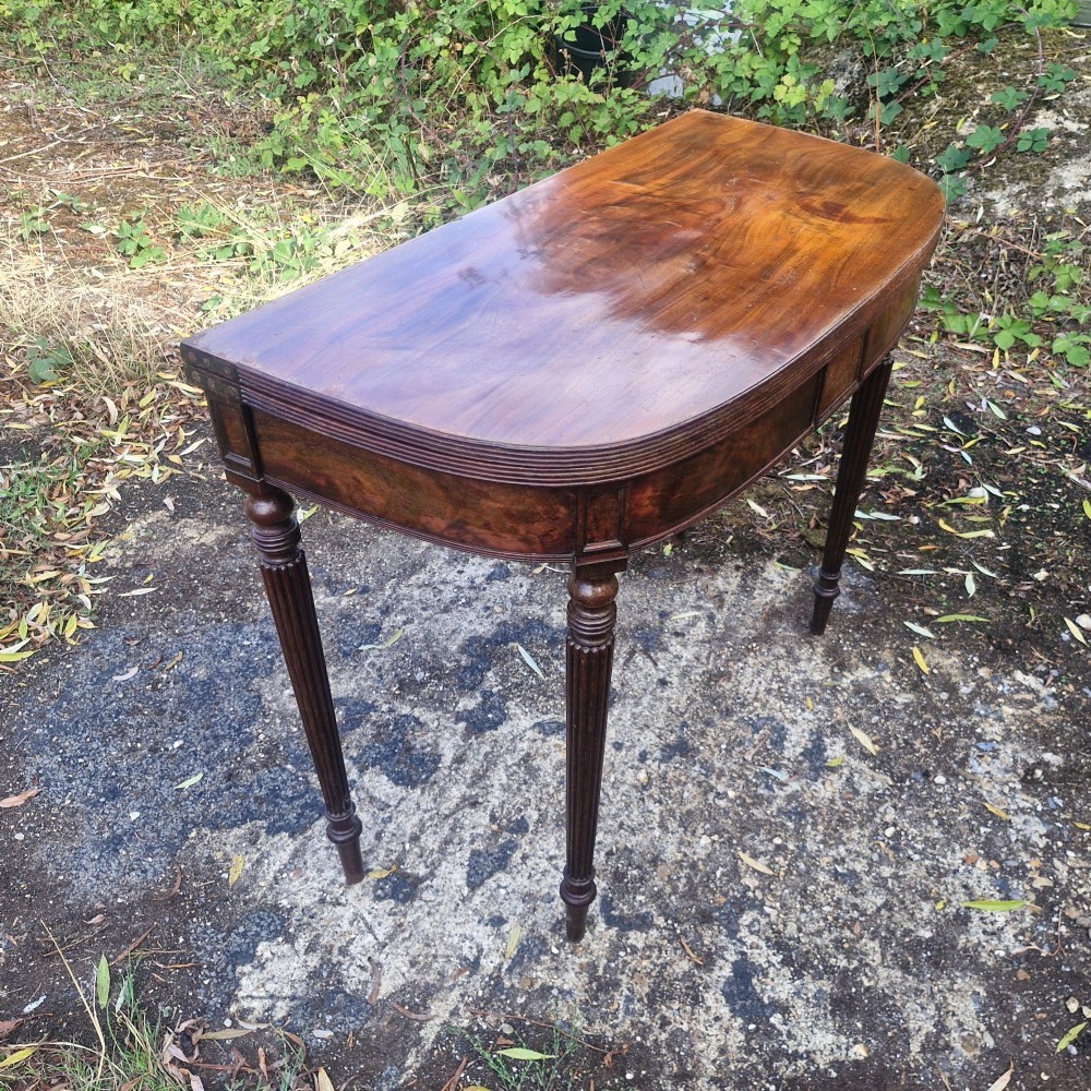 An early 19th-century mahogany demilune foldover tea table featuring a reeded apron and four reeded legs in the Gillows style. View XI