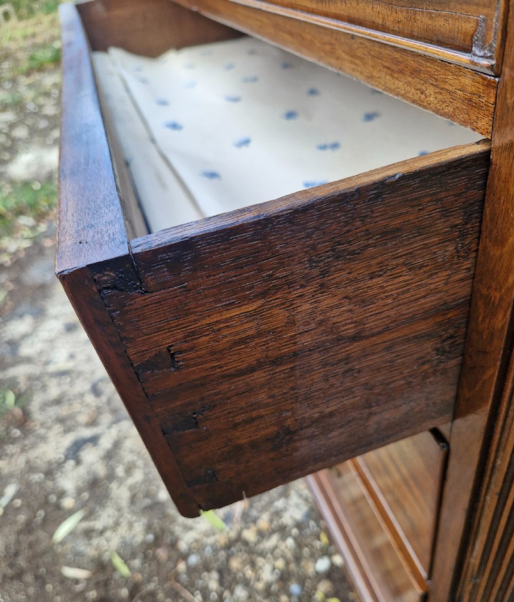A Late Georgian mahogany chest of drawers featuring a two-over-three drawer configuration, fluted pilasters, bracket feet, and brass swan-neck handles. View III