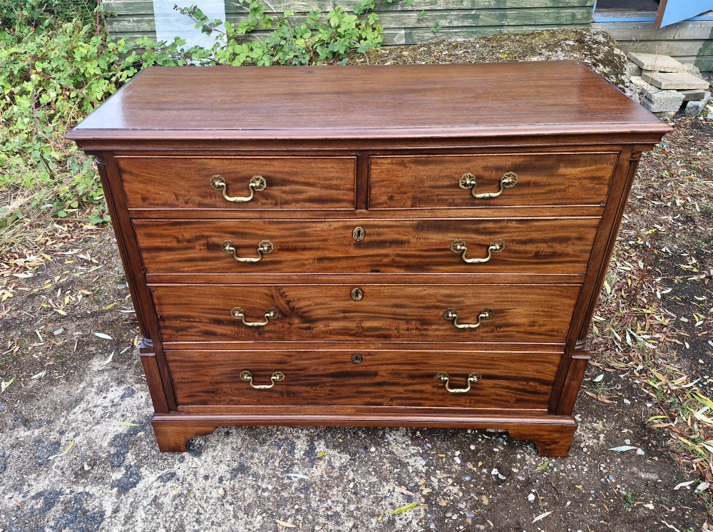 A Late Georgian mahogany chest of drawers featuring a two-over-three drawer configuration, fluted pilasters, bracket feet, and brass swan-neck handles. View VII