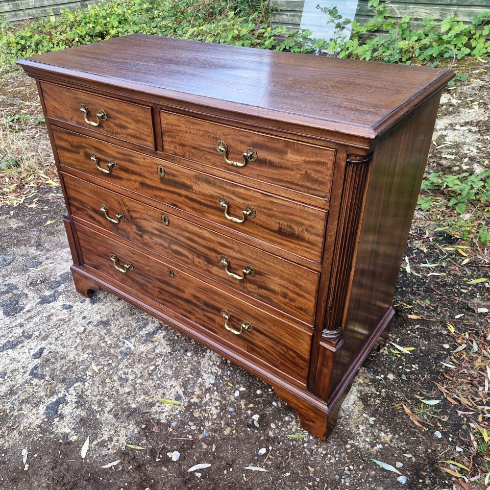 A Late Georgian mahogany chest of drawers featuring a two-over-three drawer configuration, fluted pilasters, bracket feet, and brass swan-neck handles. View VIII