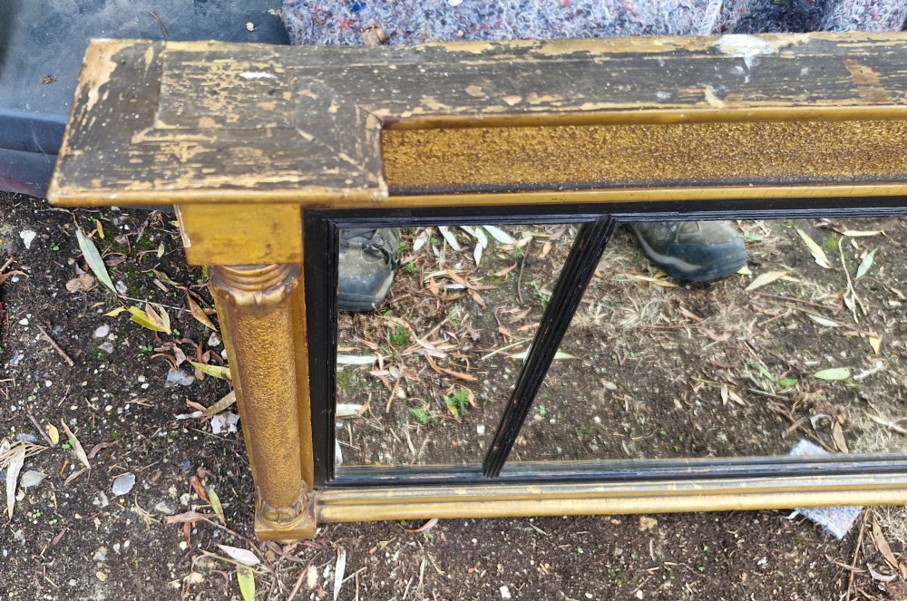 A Regency period horizontal tripartite overmantel mirror featuring a gilded architectural frame with classical fluted pilasters and an ebonised inner slip dividing three glass panels. View III