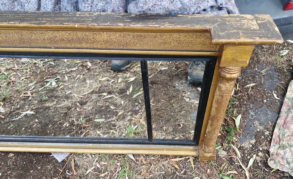 A Regency period horizontal tripartite overmantel mirror featuring a gilded architectural frame with classical fluted pilasters and an ebonised inner slip dividing three glass panels. View IV