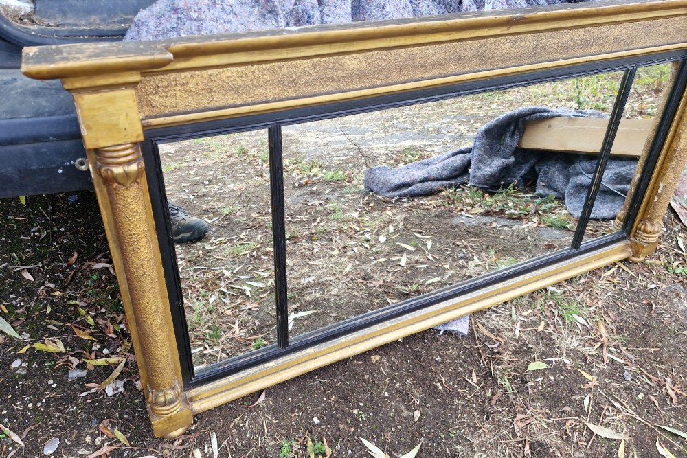 A Regency period horizontal tripartite overmantel mirror featuring a gilded architectural frame with classical fluted pilasters and an ebonised inner slip dividing three glass panels. View VIII