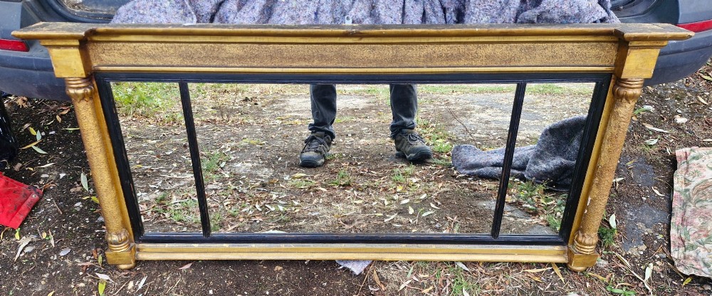 A Regency period horizontal tripartite overmantel mirror featuring a gilded architectural frame with classical fluted pilasters and an ebonised inner slip dividing three glass panels. View X