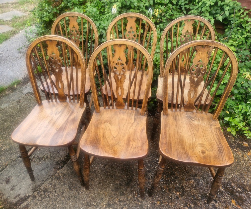 A set of six wooden Windsor dining chairs featuring hoop backs, wheelback splats, shaped solid seats, and turned legs. View V