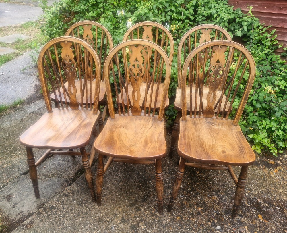 A set of six wooden Windsor dining chairs featuring hoop backs, wheelback splats, shaped solid seats, and turned legs. View VI