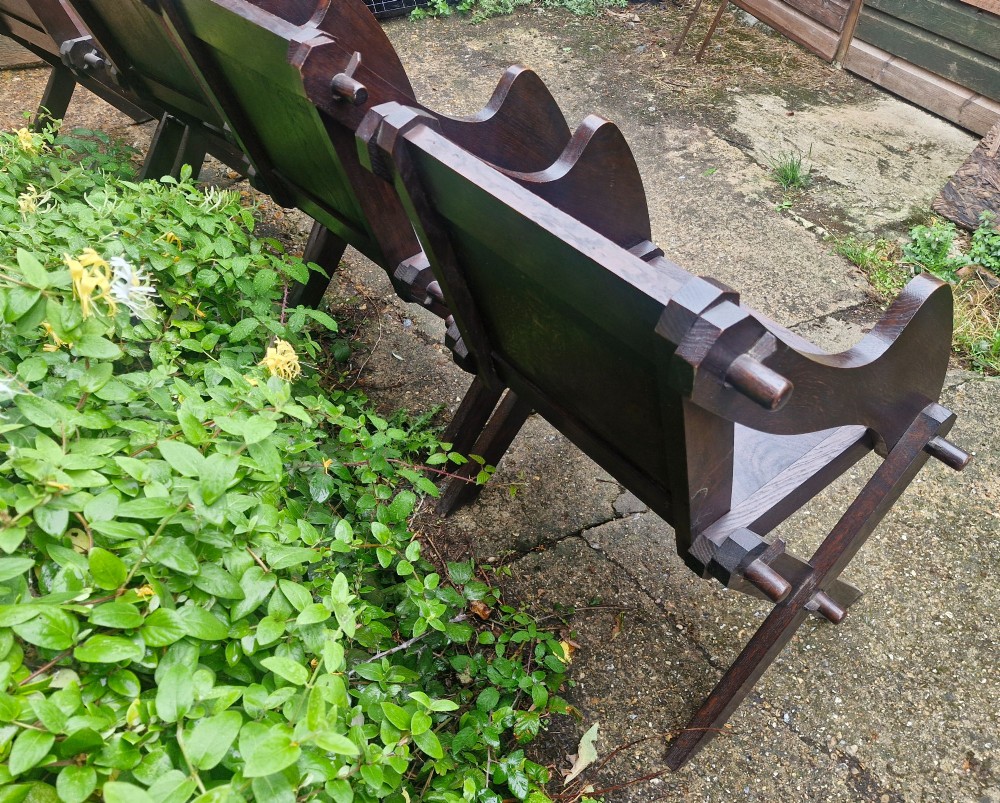 A set of four dark brown carved oak Glastonbury armchairs with X-frame legs and circular rosette backrests. View II