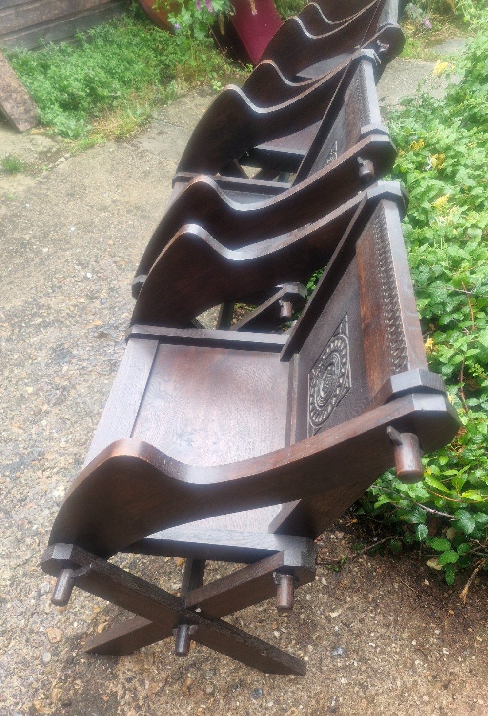 A set of four dark brown carved oak Glastonbury armchairs with X-frame legs and circular rosette backrests. View VI