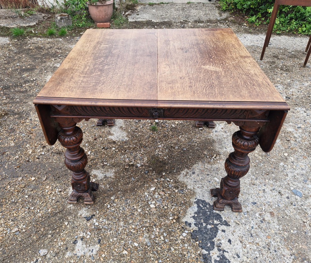 A late Victorian oak extending dining table featuring removable extension leaves, carved aprons, and turned legs. View III