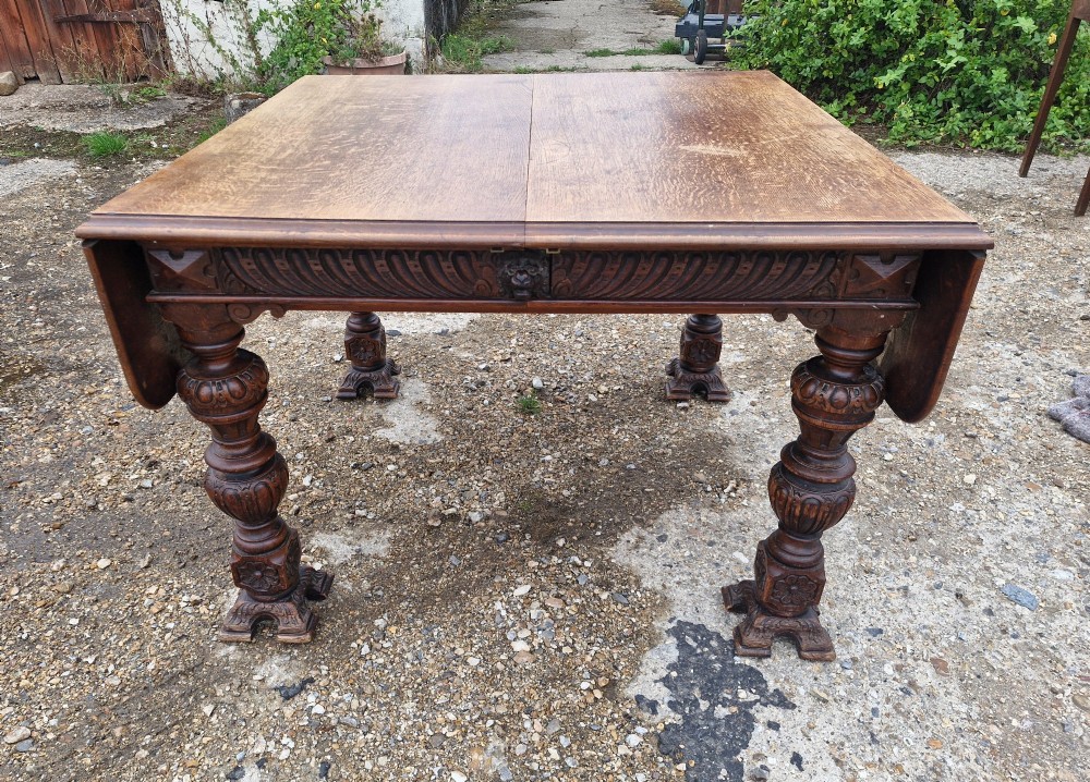 A late Victorian oak extending dining table featuring removable extension leaves, carved aprons, and turned legs. View V