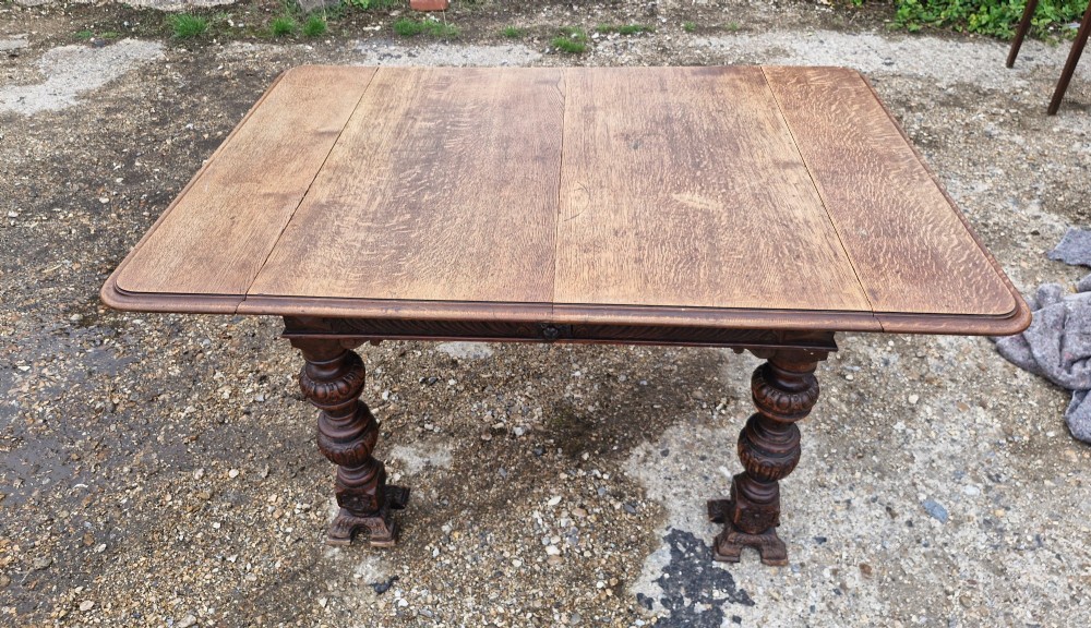 A late Victorian oak extending dining table featuring removable extension leaves, carved aprons, and turned legs. View VI
