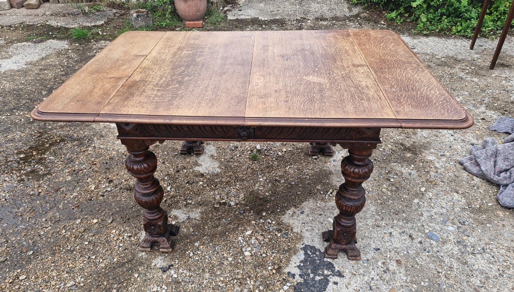 A late Victorian oak extending dining table featuring removable extension leaves, carved aprons, and turned legs. View VII