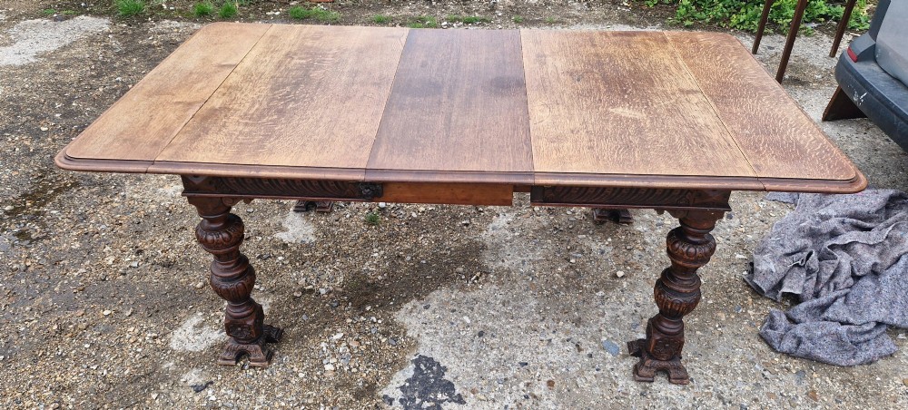 A late Victorian oak extending dining table featuring removable extension leaves, carved aprons, and turned legs. View X