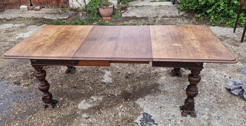 A late Victorian oak extending dining table featuring removable extension leaves, carved aprons, and turned legs. View XI