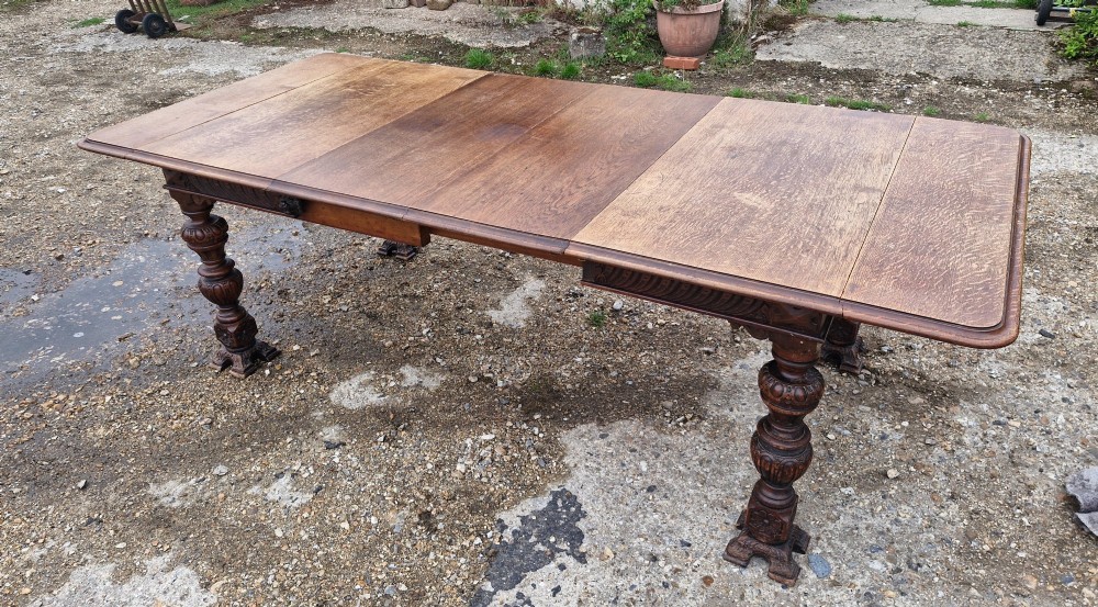 A late Victorian oak extending dining table featuring removable extension leaves, carved aprons, and turned legs. View XII