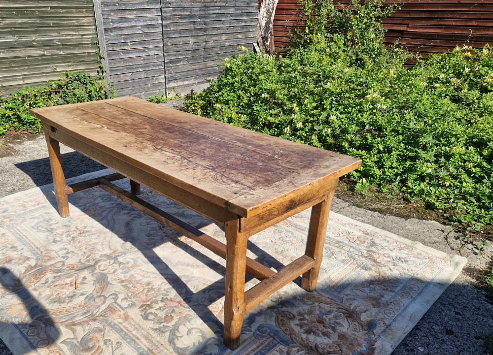 A rustic French farmhouse dining table made of weathered oak with a heavy plank top and sturdy stretcher base.