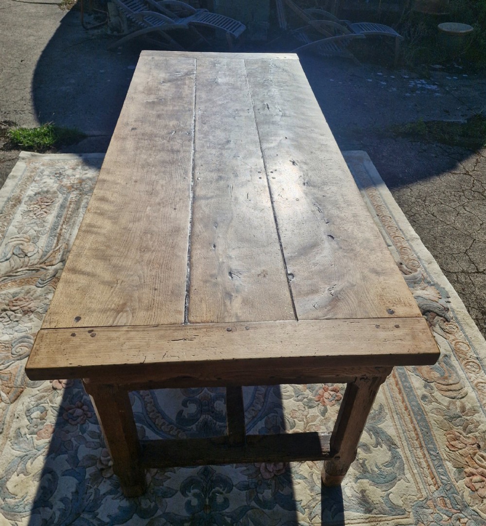 A rustic French farmhouse dining table made of weathered oak with a heavy plank top and sturdy stretcher base. View II