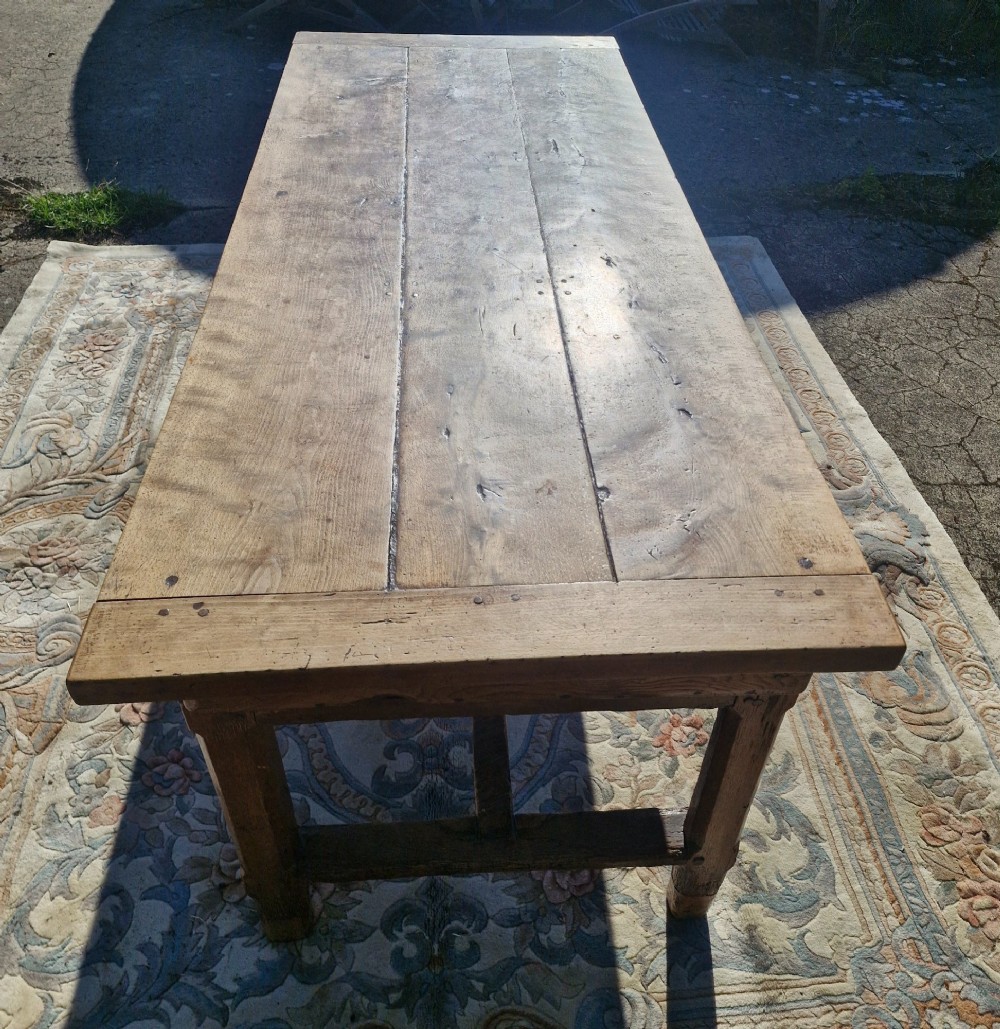 A rustic French farmhouse dining table made of weathered oak with a heavy plank top and sturdy stretcher base. View III