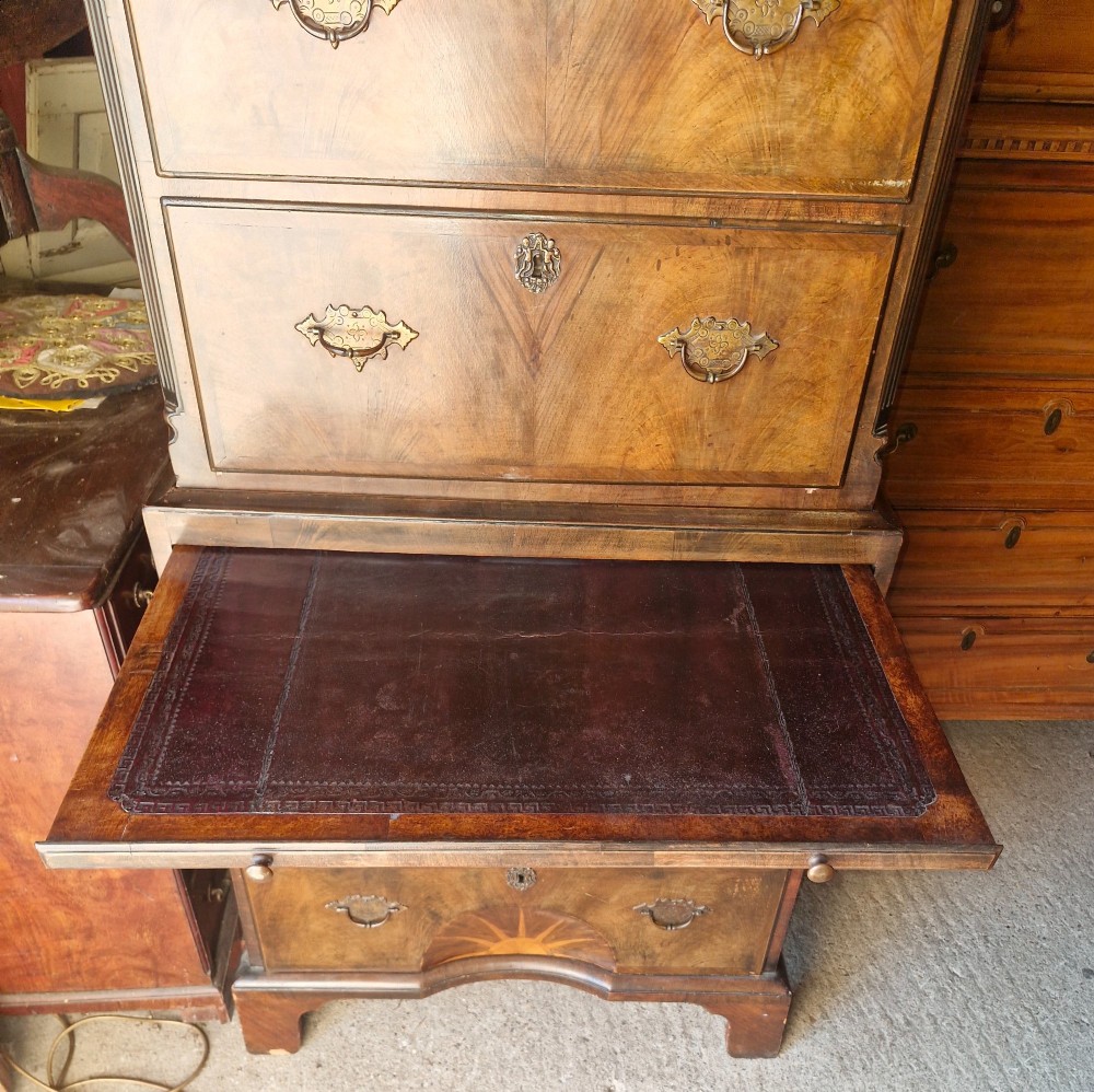 An early 20th century walnut chest on chest featuring brass drop handles, a pull-out brushing slide, and an inlaid sunburst motif on the lower drawer. View IV
