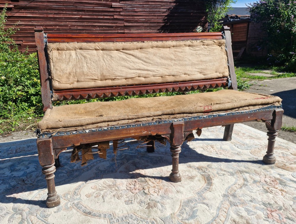 A Victorian mahogany hall bench featuring a padded backrest and seat upholstered in hessian cloth, supported by turned front legs and carved wooden trim. View III