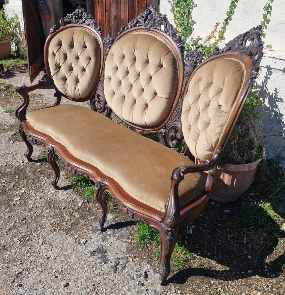 A 19th-century mahogany conversation sofa featuring three oval button-back upholstered panels, intricate carved frame detailing, cabriole legs, and velvet seating. View III