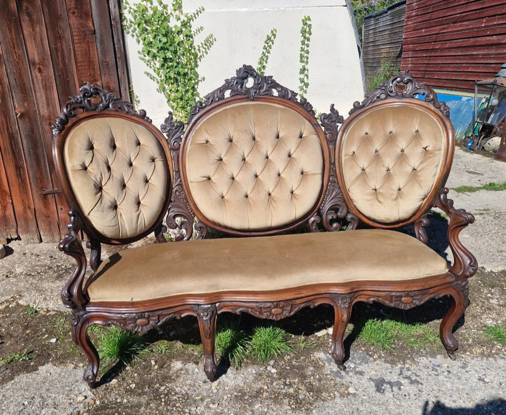 A 19th-century mahogany conversation sofa featuring three oval button-back upholstered panels, intricate carved frame detailing, cabriole legs, and velvet seating. View IV