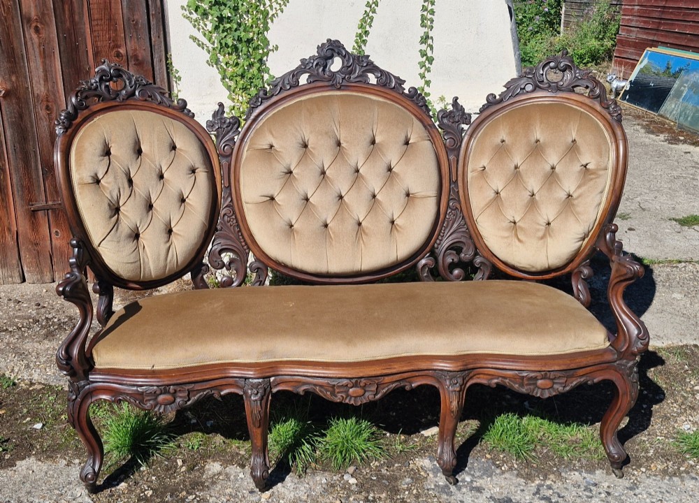 A 19th-century mahogany conversation sofa featuring three oval button-back upholstered panels, intricate carved frame detailing, cabriole legs, and velvet seating. View V