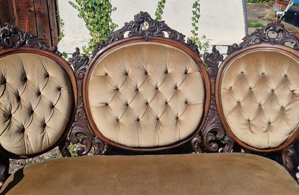 A 19th-century mahogany conversation sofa featuring three oval button-back upholstered panels, intricate carved frame detailing, cabriole legs, and velvet seating. View VI