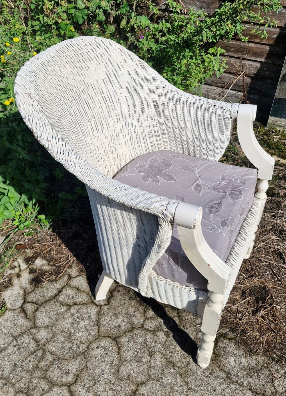 A painted off-white woven Lloyd Loom armchair featuring turned front legs, wooden arm supports, and a removable patterned fabric seat cushion. View III