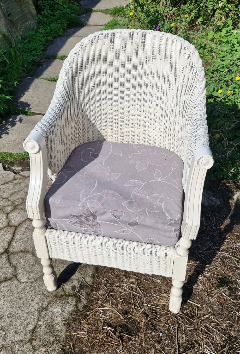 A painted off-white woven Lloyd Loom armchair featuring turned front legs, wooden arm supports, and a removable patterned fabric seat cushion. View IV
