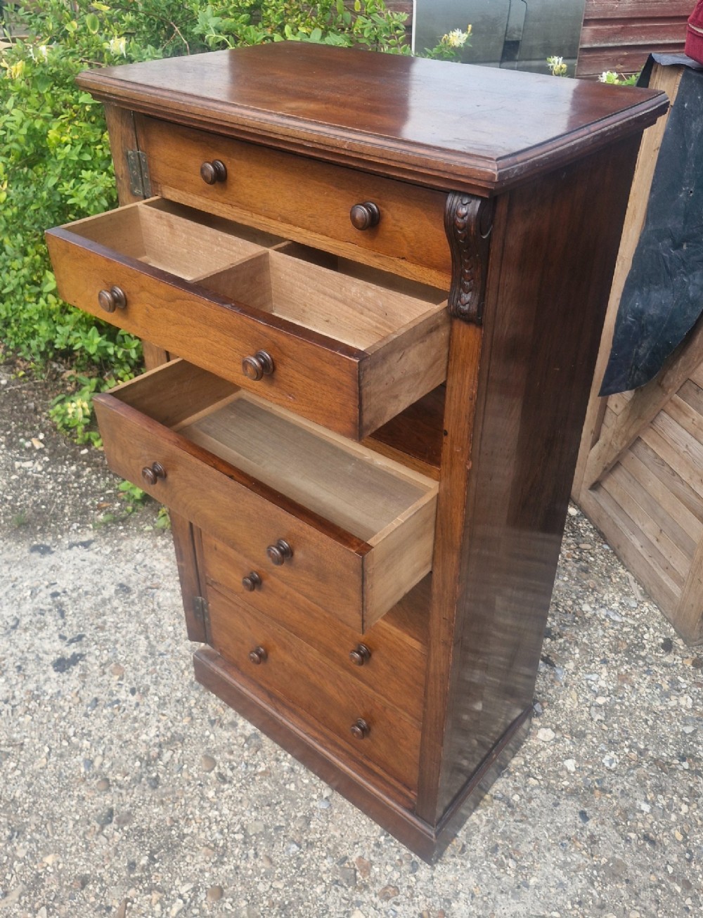 A tall, narrow mahogany Wellington chest with seven drawers featuring turned wooden knobs and carved corbels. View II