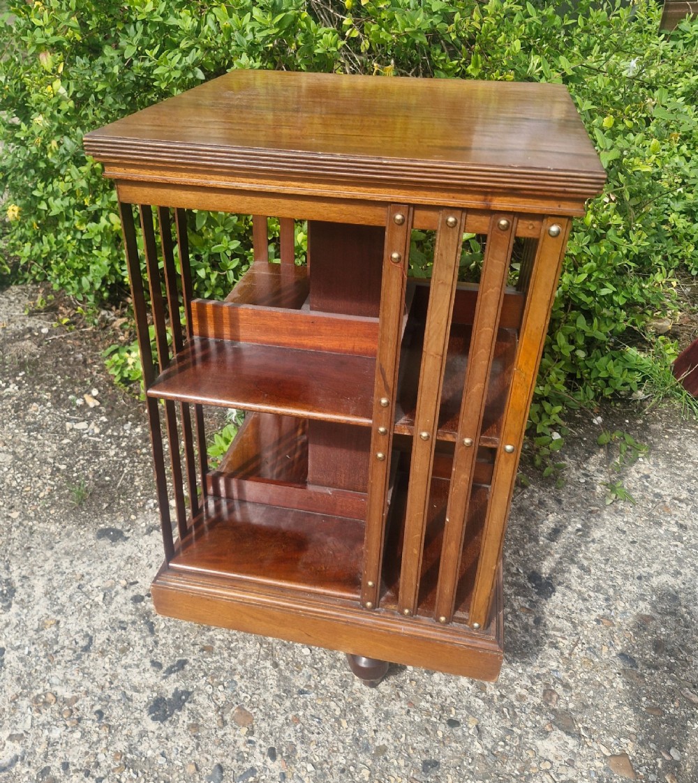 A late Victorian mahogany revolving bookcase featuring two square open tiers with vertical slatted sides fixed by brass studs. View III