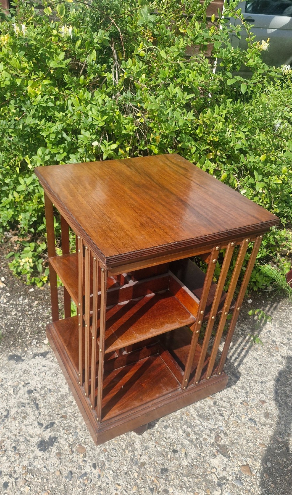 A late Victorian mahogany revolving bookcase featuring two square open tiers with vertical slatted sides fixed by brass studs. View IV