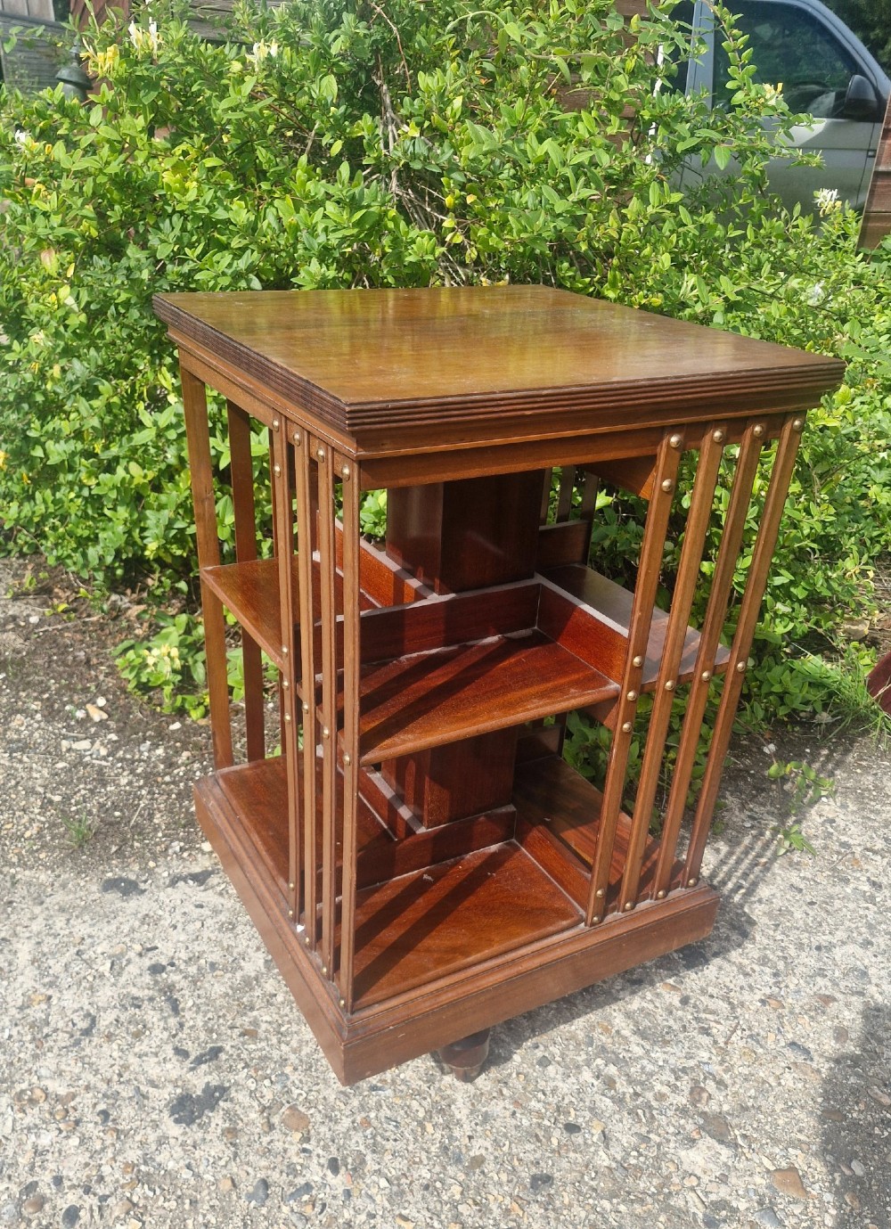 A late Victorian mahogany revolving bookcase featuring two square open tiers with vertical slatted sides fixed by brass studs. View V