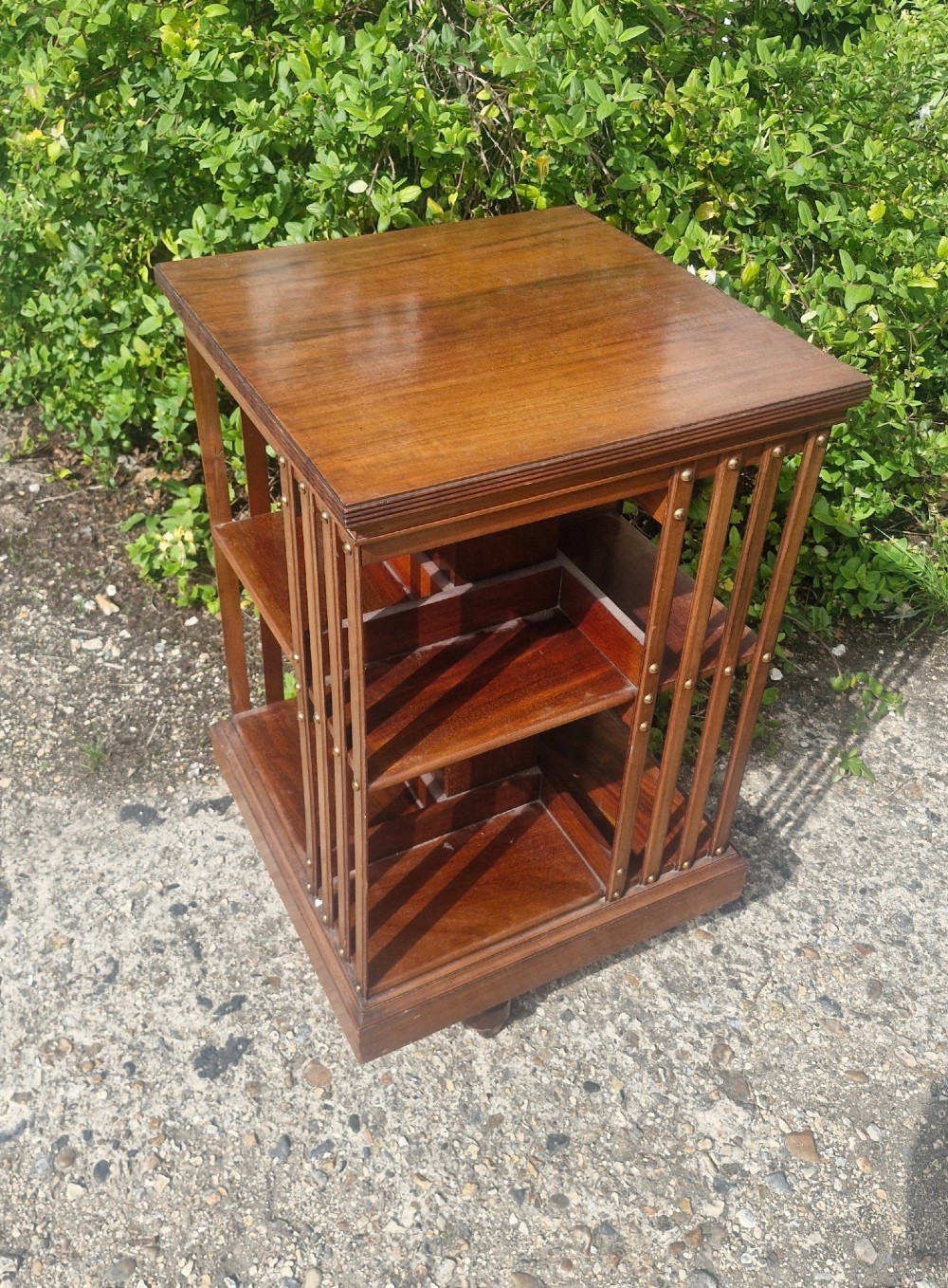A late Victorian mahogany revolving bookcase featuring two square open tiers with vertical slatted sides fixed by brass studs. View VI