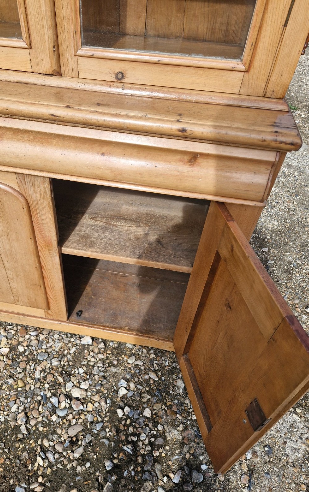 An early Victorian pine glazed bookcase featuring arched glass upper doors above a lower two-door cupboard base. View III