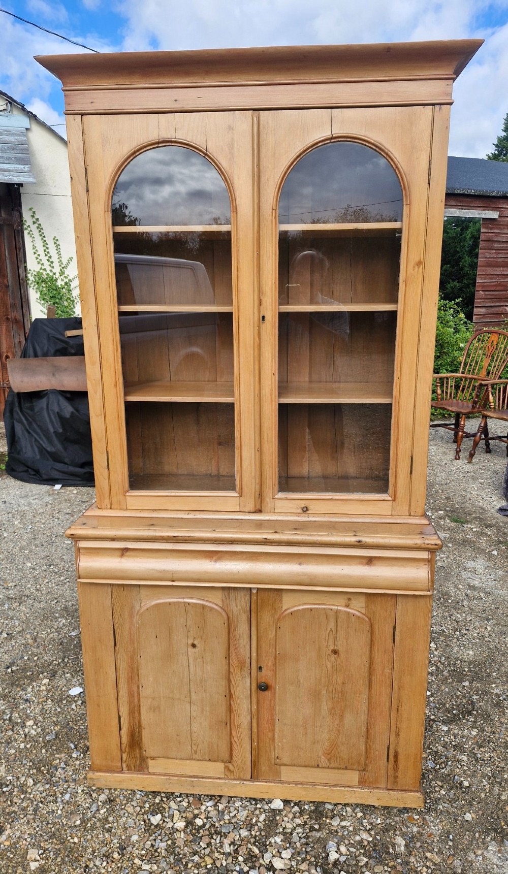 An early Victorian pine glazed bookcase featuring arched glass upper doors above a lower two-door cupboard base. View VII