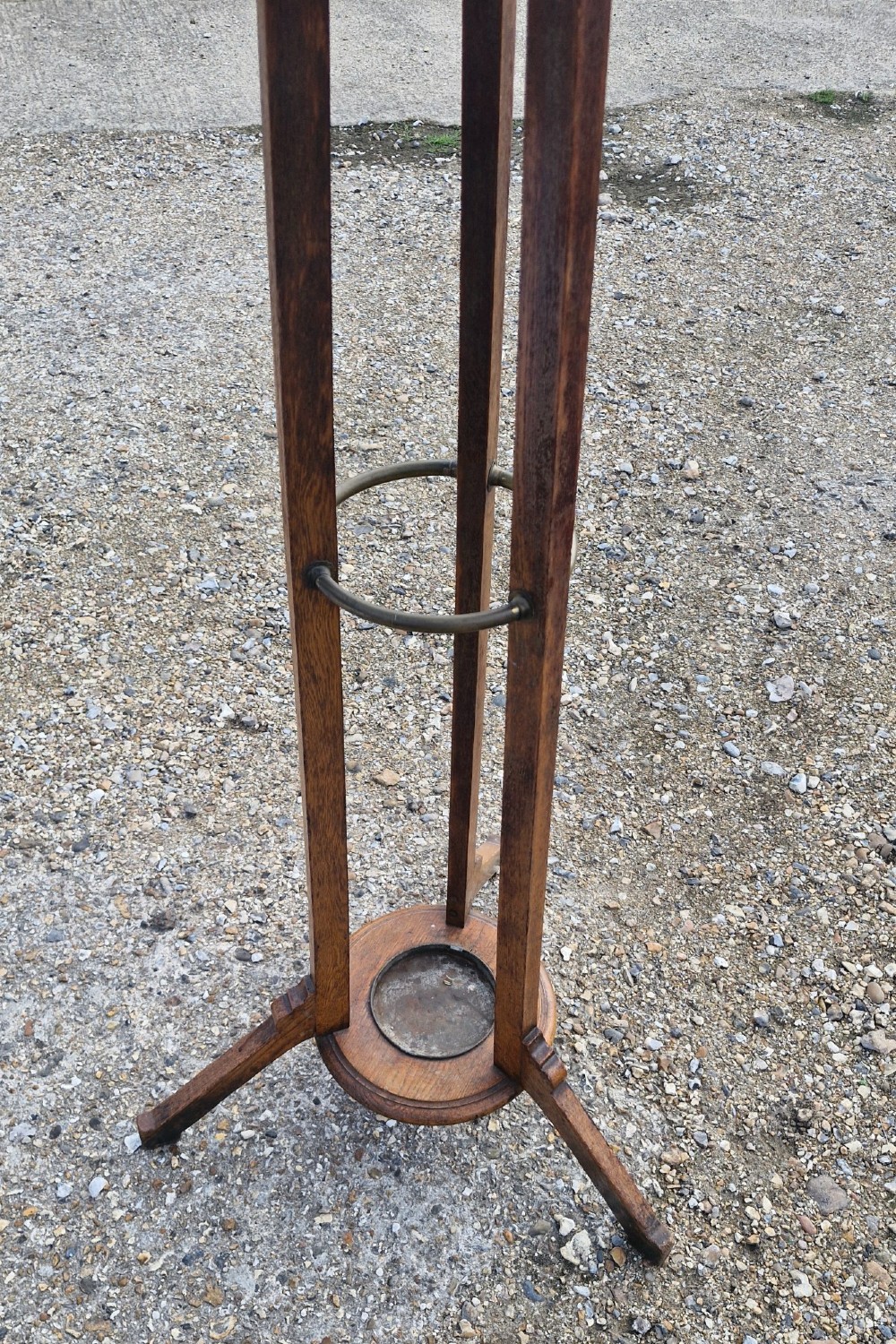 An Edwardian freestanding oak hat and coat stand featuring a revolving circular top with metal hooks, tapered tripod legs, and a bottom umbrella drip tray. View II