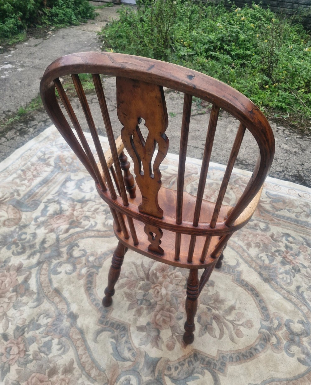 A Victorian high back wooden Windsor armchair featuring a hoop back, central pierced splat, turned spindles, curved armrests, a contoured seat, and turned legs. View II