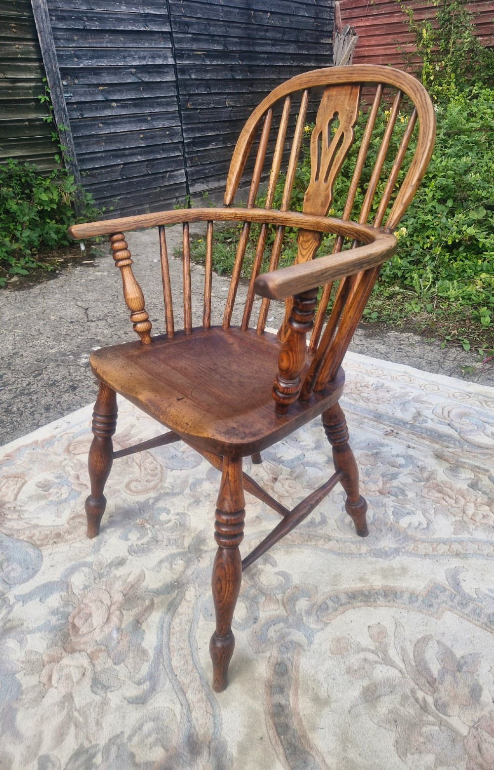 A Victorian wooden Windsor armchair with a bow back, turned spindles, a pierced central splat, integrated armrests, and a contoured saddle seat on turned legs. View II