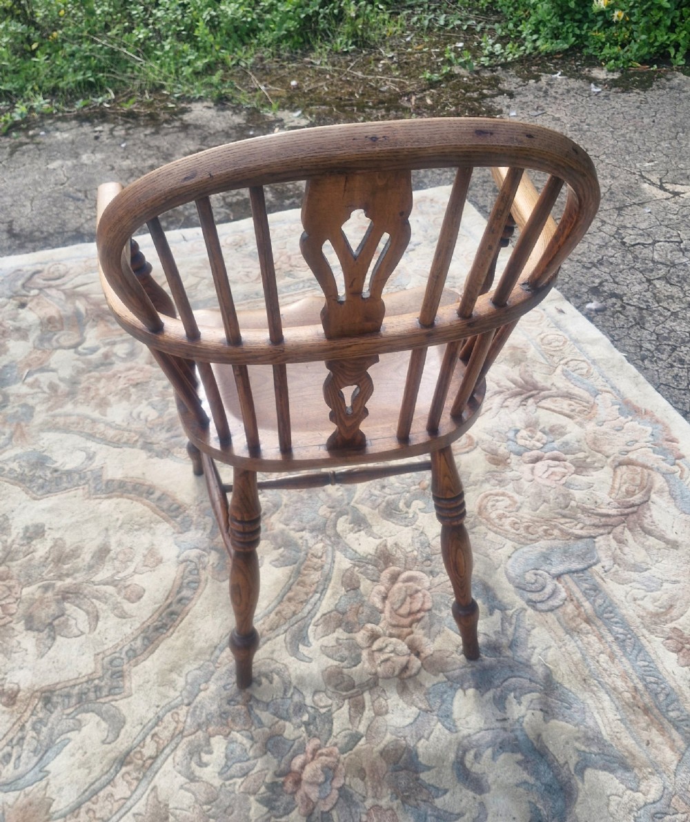 A Victorian wooden Windsor armchair with a bow back, turned spindles, a pierced central splat, integrated armrests, and a contoured saddle seat on turned legs. View VI