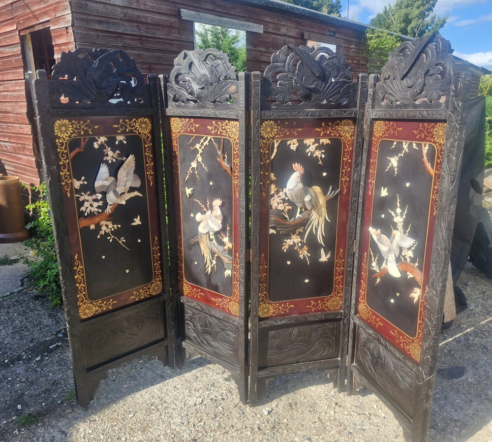 A four-panel dark wood folding screen featuring carved openwork top crests and central dark panels with raised bone inlays depicting birds among flowering branches.