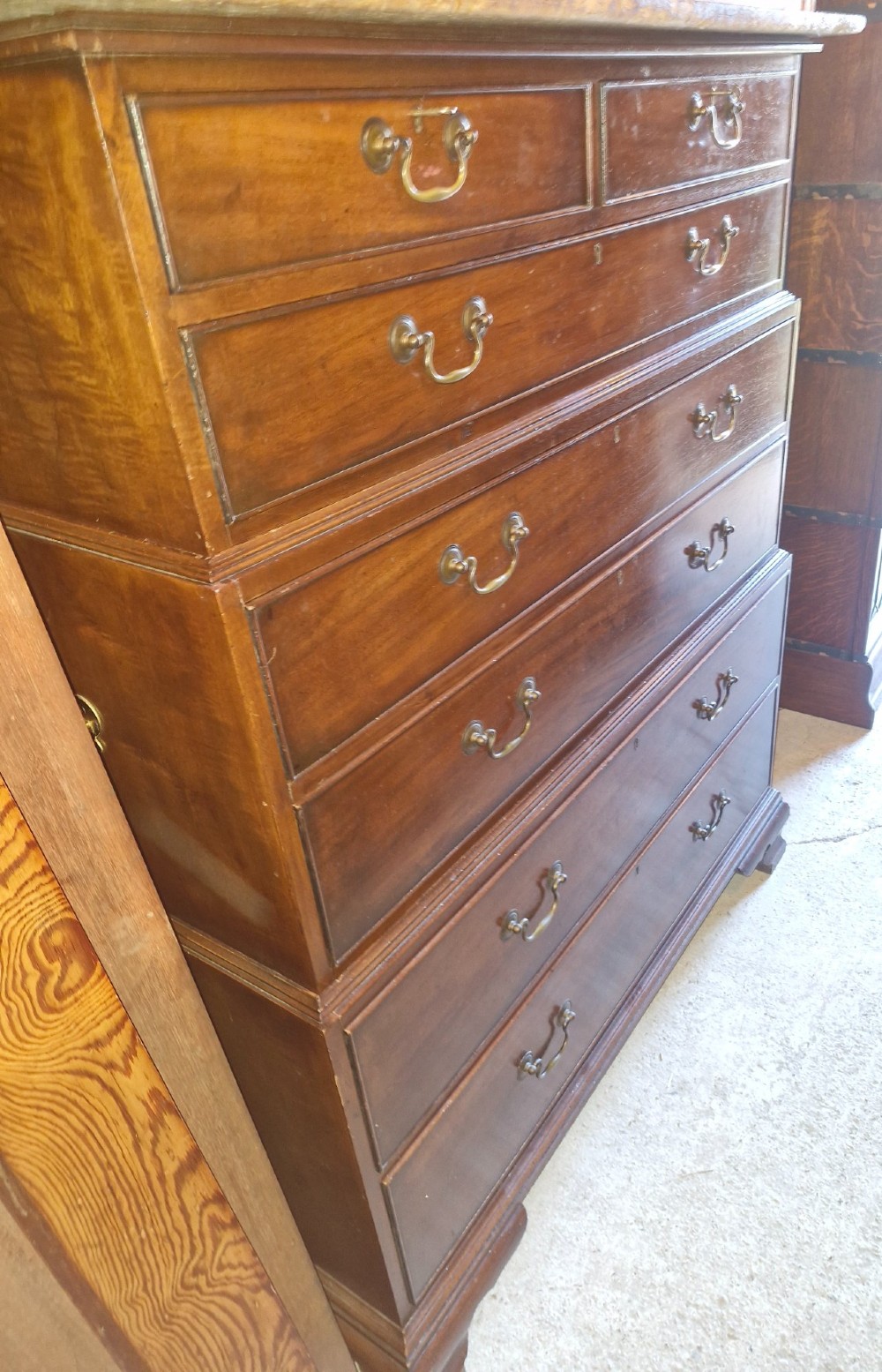 A three-part mahogany campaign style chest of drawers featuring brass handles, side carrying brackets, and bracket feet. View VII