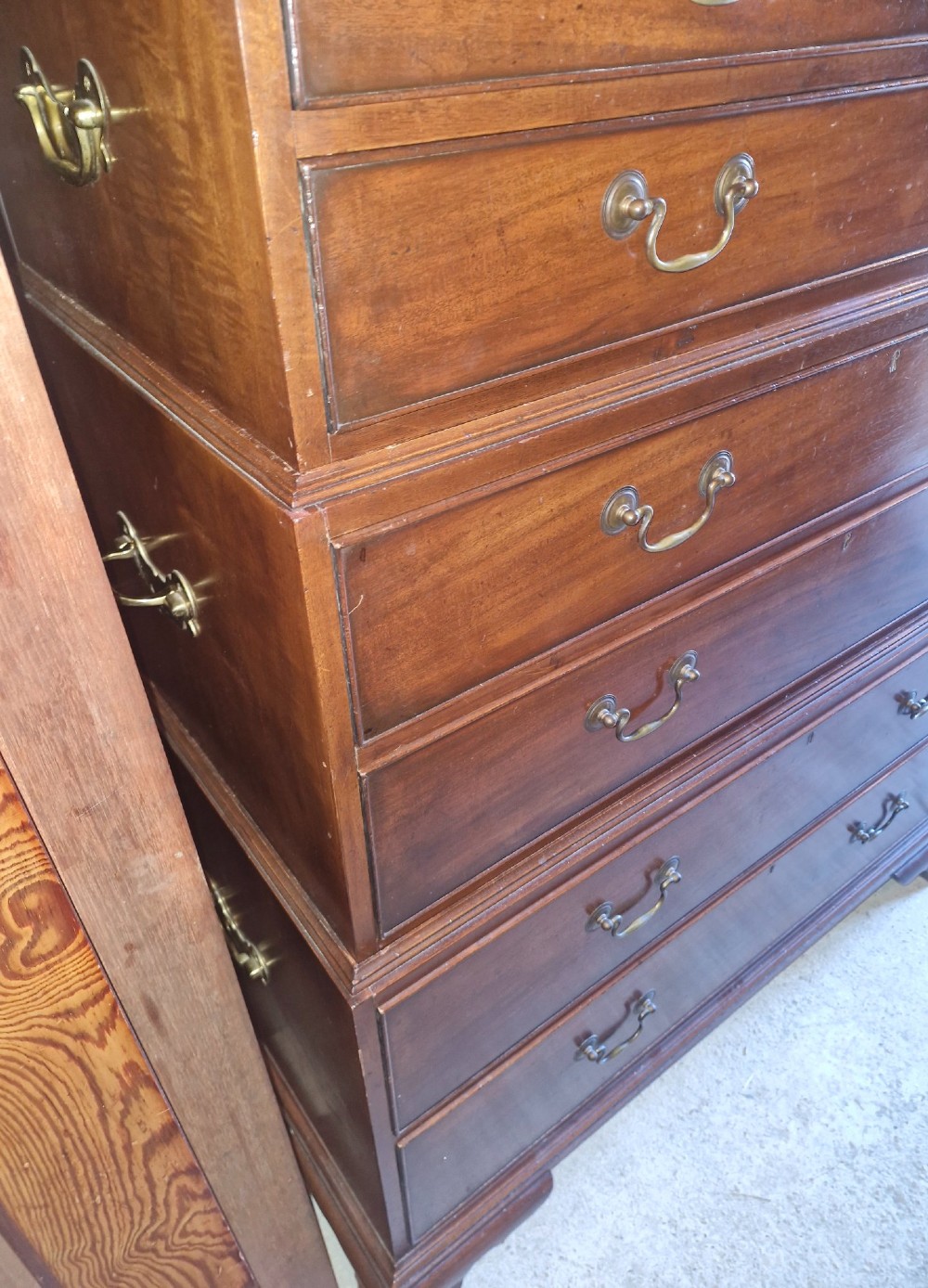 A three-part mahogany campaign style chest of drawers featuring brass handles, side carrying brackets, and bracket feet. View VIII