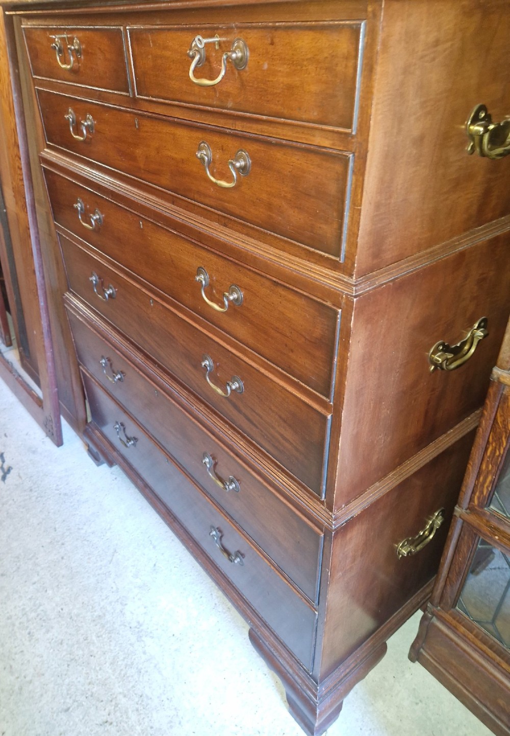 A three-part mahogany campaign style chest of drawers featuring brass handles, side carrying brackets, and bracket feet. View IX