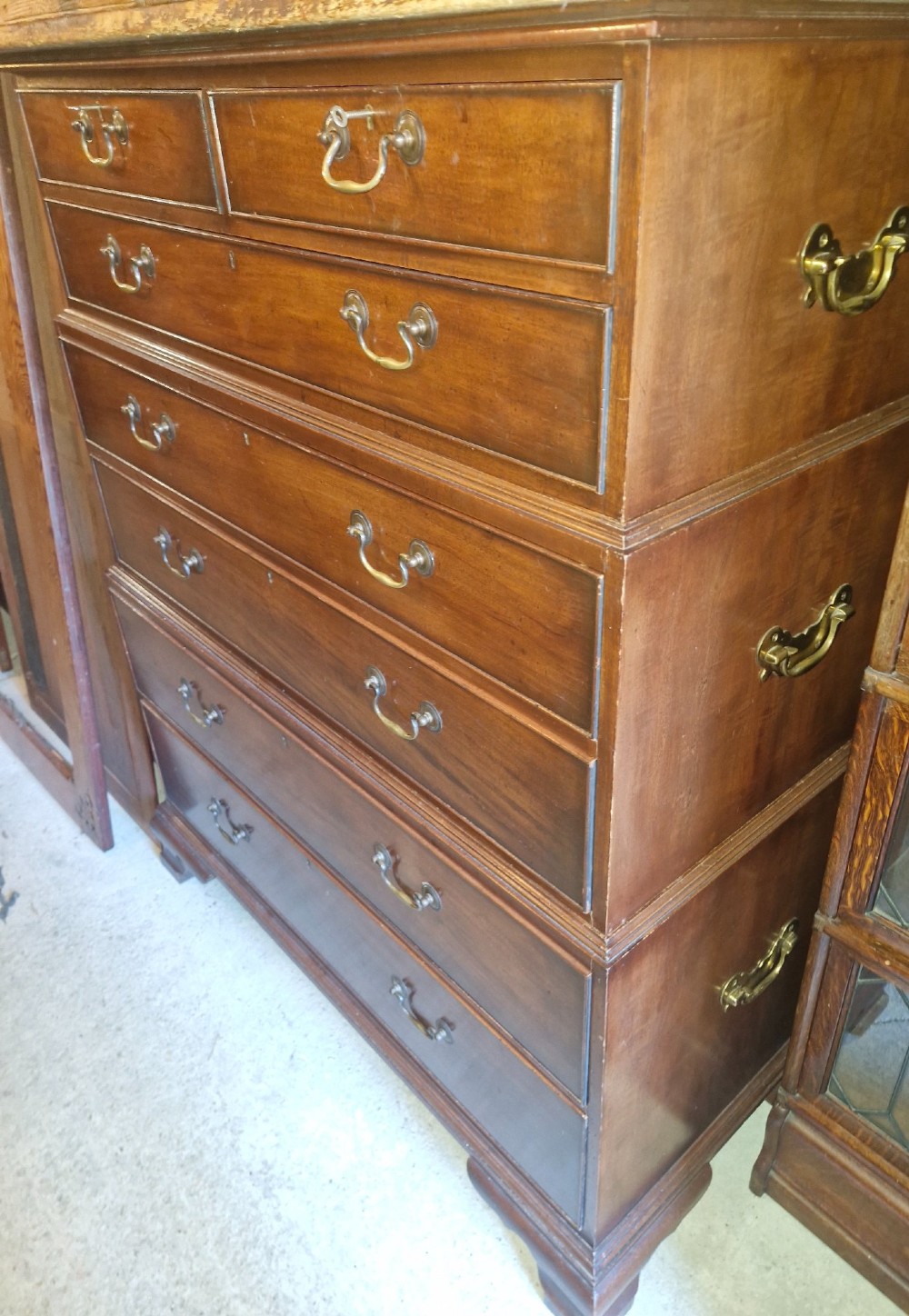 A three-part mahogany campaign style chest of drawers featuring brass handles, side carrying brackets, and bracket feet. View X