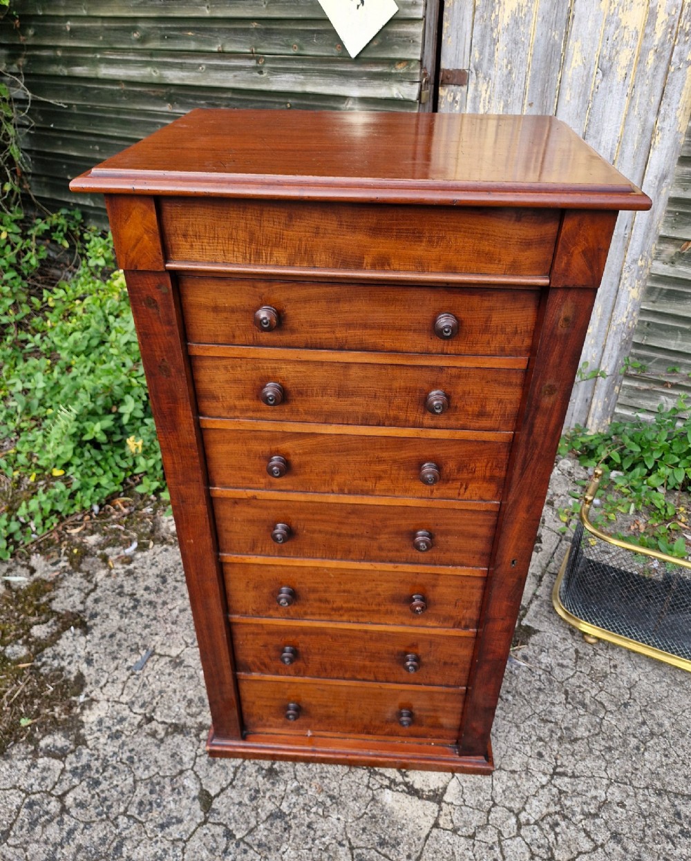 A tall Victorian mahogany Wellington chest featuring seven graduated drawers, turned wooden handles, and a hinged side locking flap. View II