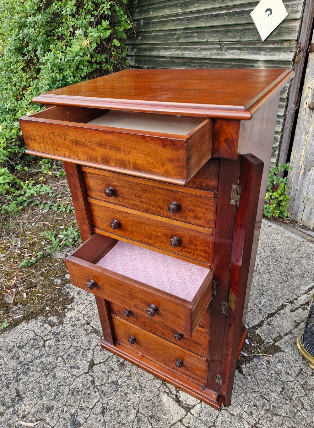 A tall Victorian mahogany Wellington chest featuring seven graduated drawers, turned wooden handles, and a hinged side locking flap. View III