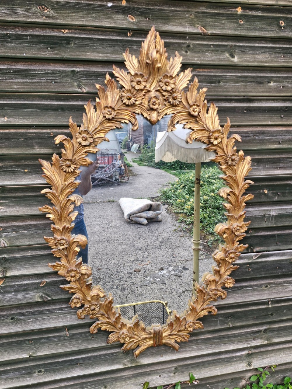 An oval wall mirror featuring a carved giltwood frame decorated with detailed acanthus leaves and floral motifs.
