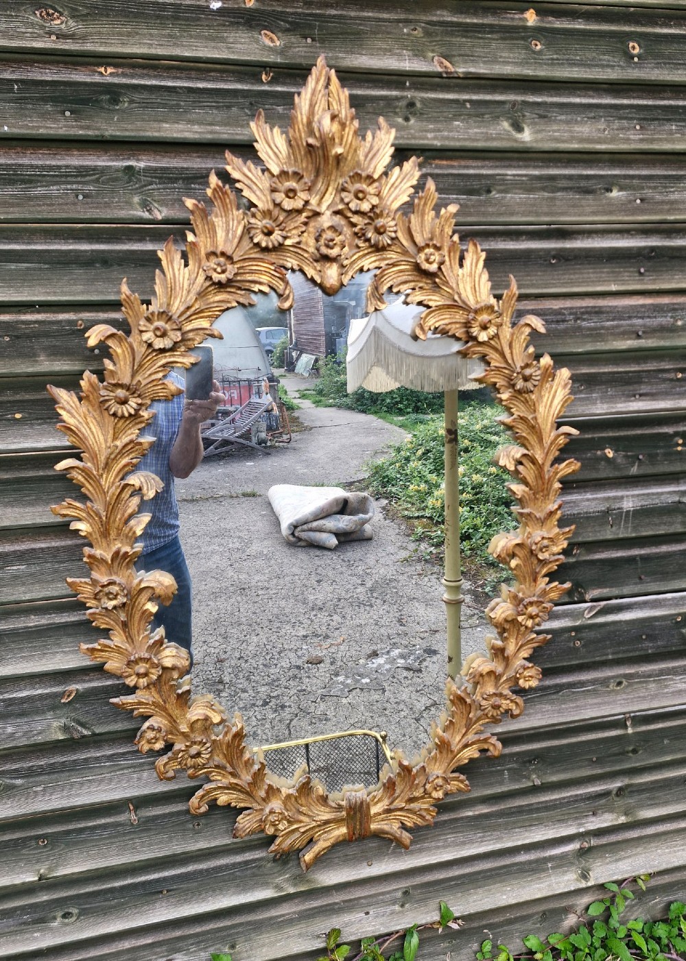 An oval wall mirror featuring a carved giltwood frame decorated with detailed acanthus leaves and floral motifs. View II